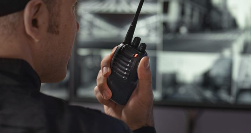 Security guard on duty with a two-way radio at an industrial site
